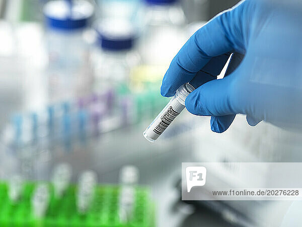 Hand of mature scientist holding DNA sample in vial at laboratory