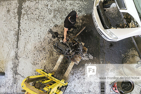 Mechanic disassembling vehicle machine parts at workshop