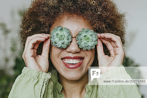 Smiling young woman wearing echeveria flowers eyeglasses