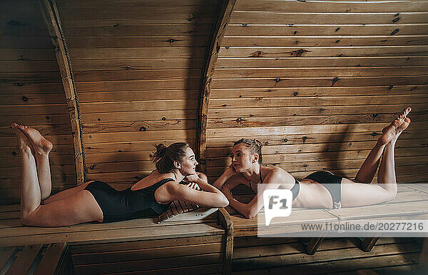 Friends relaxing on bench at sauna