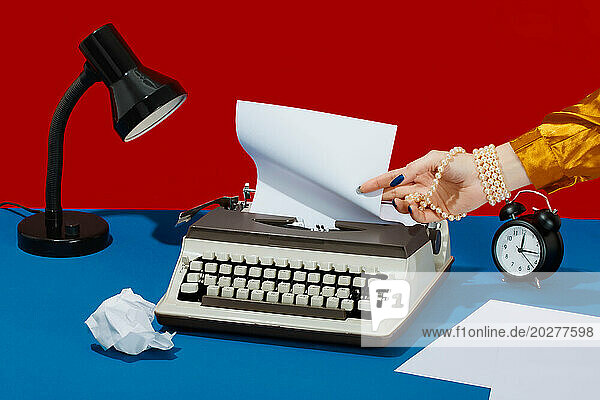 Writer removing paper from typewriter on desk