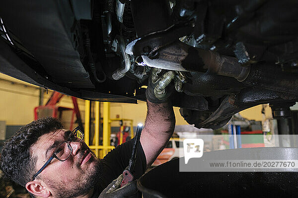 Mechanic inspecting lifted vehicle at workshop