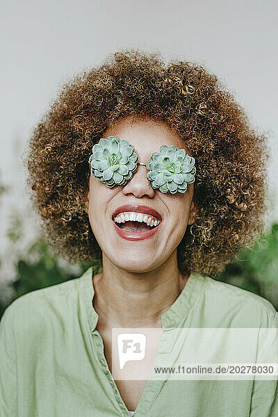 Cheerful woman wearing echeveria flowers eyeglasses
