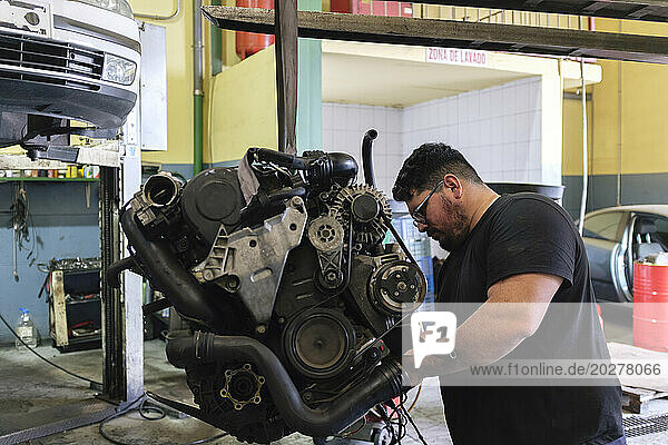 Mechanic disassembling vehicle engine at workshop