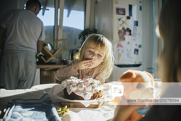Girl enjoying birthday cake on table at home