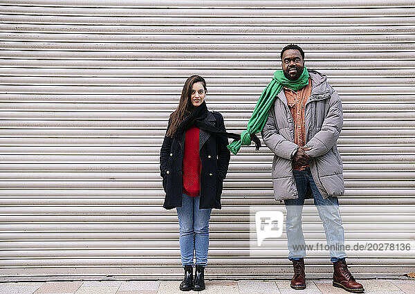 Couple standing with tied scarves in front of shutter