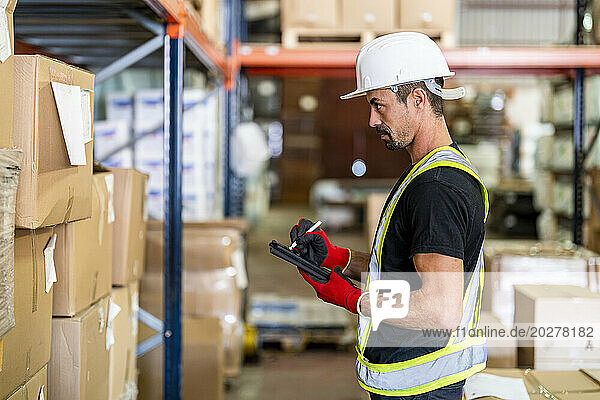 Worker taking inventory on tablet PC at warehouse