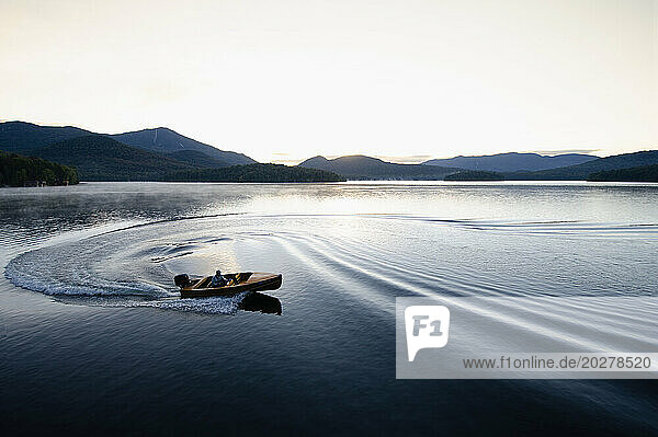 USA  New York  Lake Placid  Man in wooden boat on lake at sunrise