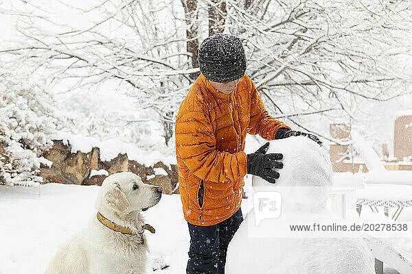 Boy with his dog building snowman