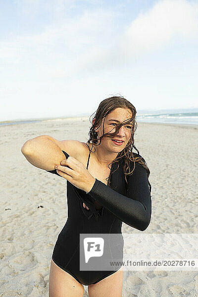 South Africa  Hermanus  Teenage girl putting on wetsuit on beach