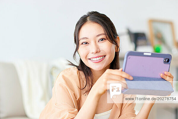 Asian woman using tablet computer at home