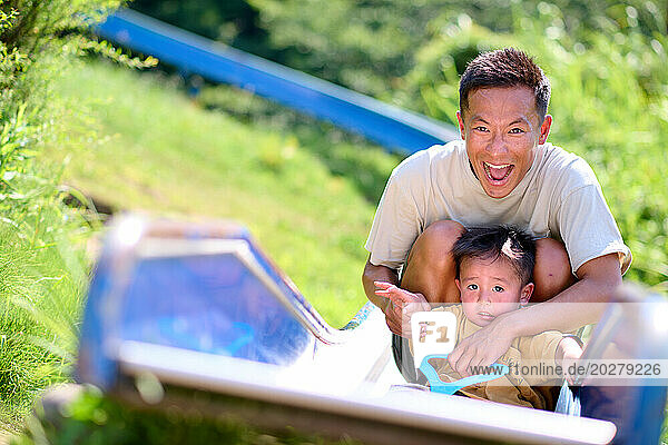 A man and a child on a slide in the grass
