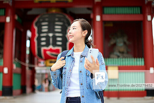 A woman in a denim jacket standing in front of a temple