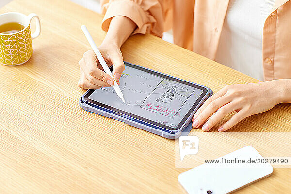 A woman writing on a tablet with a pen