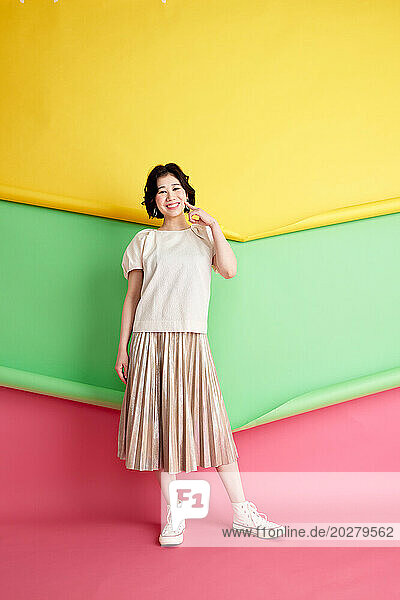 Asian woman in a skirt posing against colorful wall