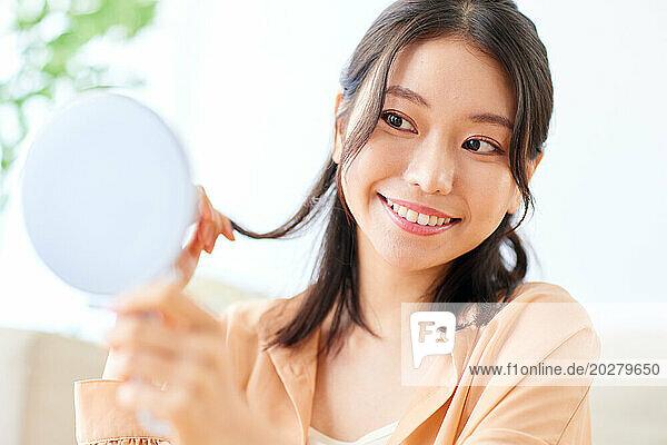 Asian woman smiling while holding a mirror