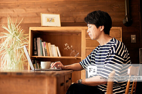 A man in striped shirt sitting at a table with a laptop