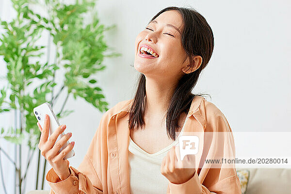 Asian woman laughing while using her cell phone