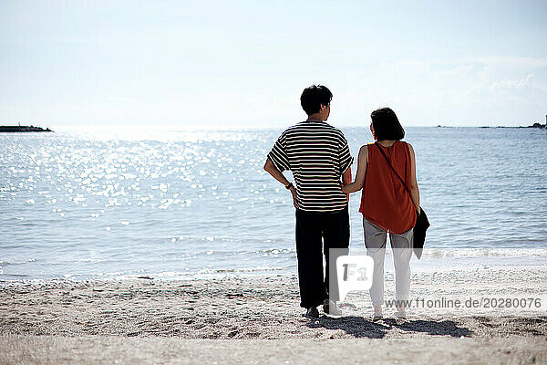 A couple standing on the beach looking at the ocean