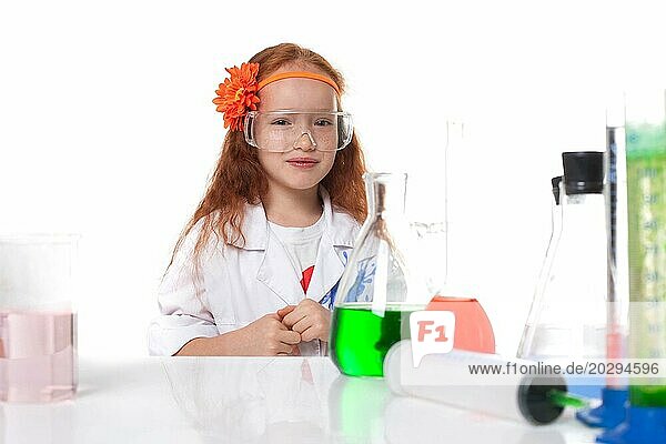 Lächelndes rothaariges Schulmädchen posiert im Labor  vor weißem Hintergrund