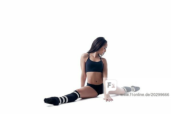 Studioaufnahme eines flexiblen schlanken Mädchens  das auf einem Spalt sitzt  vor weißem Hintergrund