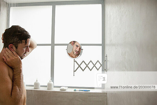 Man under Shower Looking in Mirror
