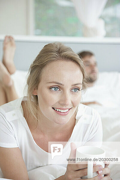 Woman Lying on Bed Holding Mug