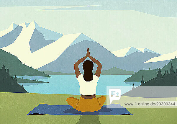Serene woman meditating on yoga mat in grass overlooking idyllic  scenic mountain and lake