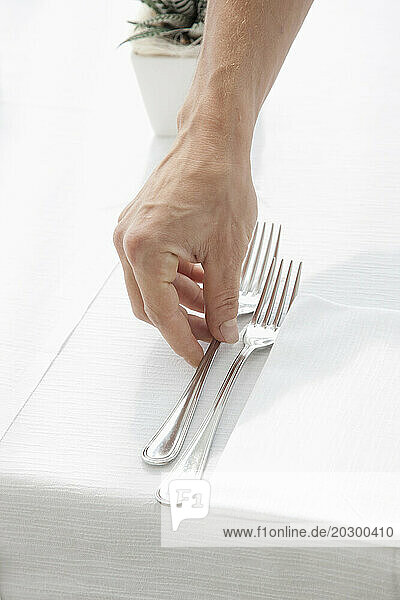 Close up of Waiter's Hand Arranging Cutlery on Restaurant Table
