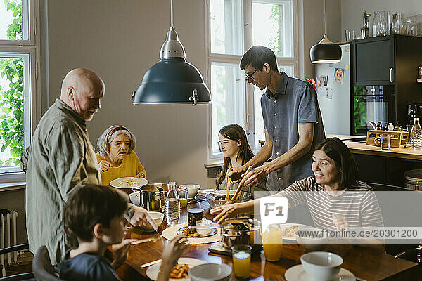 Multi-generation family having dinner at dining table in home