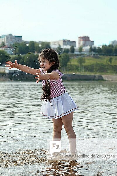 Bild von lustigen kleinen Mädchen spielt mit Wasser spritzt