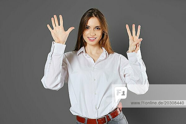 Junge Frau hebt beide Hände hoch und zeigt acht Finger. Zählen mit Fingern Konzept