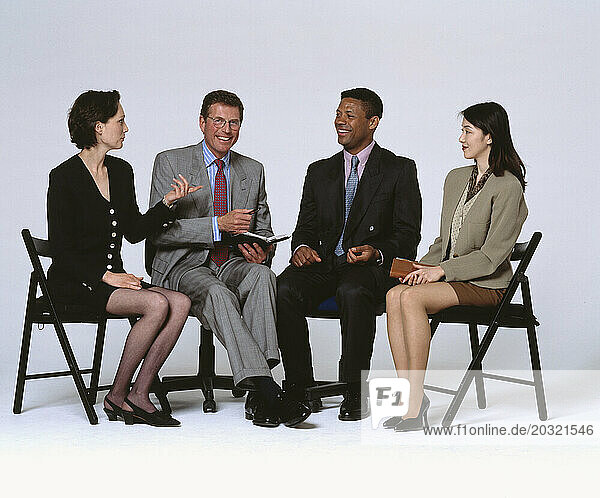 Business & Professions. Row of four people sitting on occasional folding chairs.
