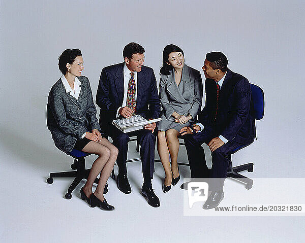 Business & Professions. Row of four people sitting on office chairs.