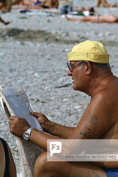 United Kingdom. England. Southend. Close up of man reading newspaper at the beach.