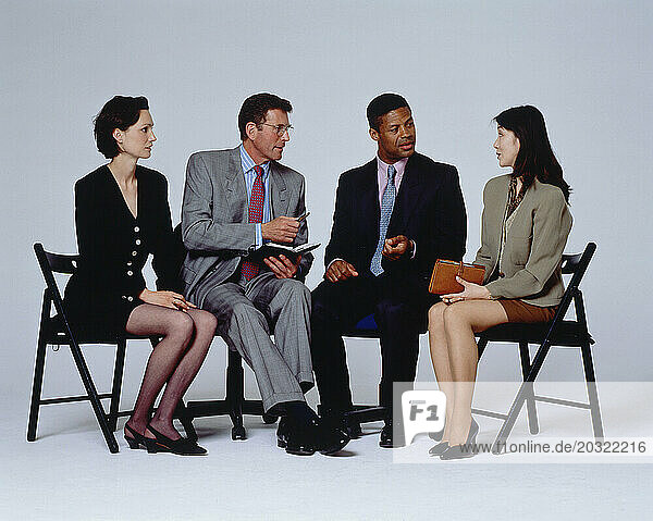 Business & Professions. Row of four people sitting on occasional folding chairs.