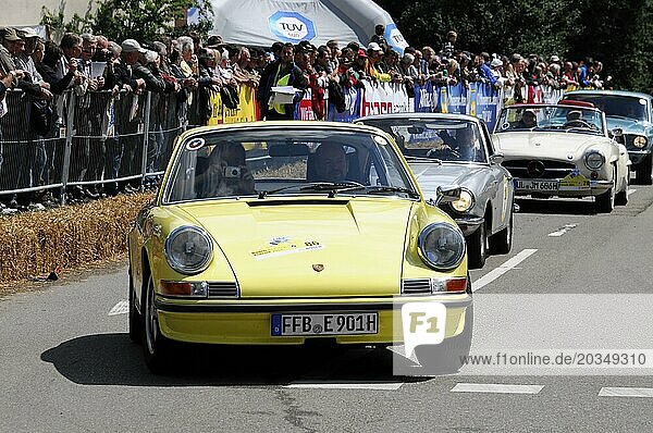 A yellow Porsche 911 classic car takes part in a street race with a view of the crowd  SOLITUDE REVIVAL 2011  Stuttgart  Baden-Württemberg  Germany  Europe