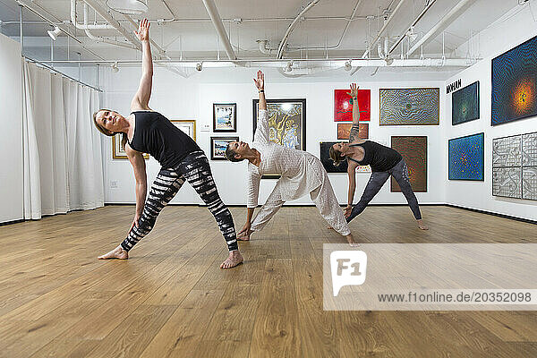 Three Women In Triangle Pose Yoga Asana In An Art Gallery