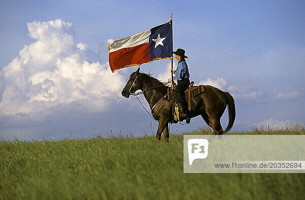 Woman on horseback with Texas Flag.