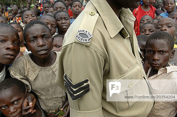Refugee children stand behind a police officer.