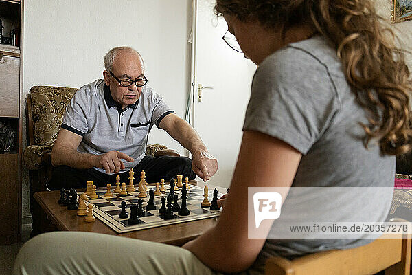 grandfather and granddaughter play chess. Visit of grandchildren