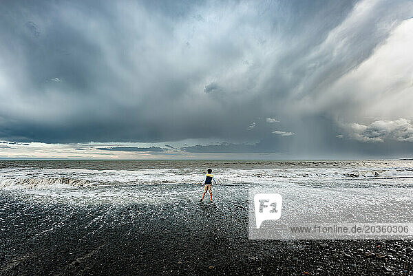Boy at rocky beach with stormy sky