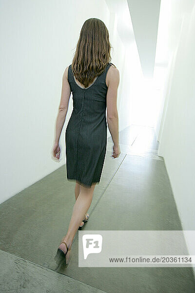 A woman walking through a long hallway.