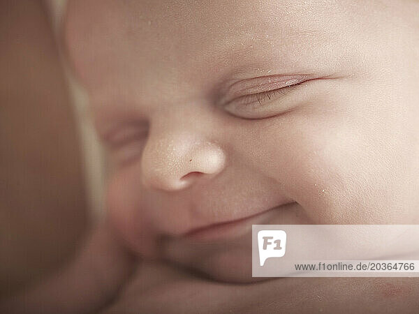 Close-up of little new born baby smiling while asleep