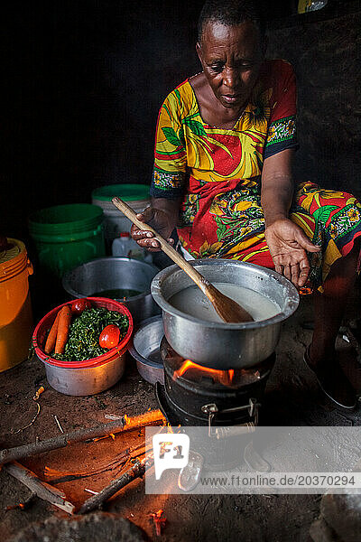 Tanzanian woman cooking dinner of ugali  vegetables and beans