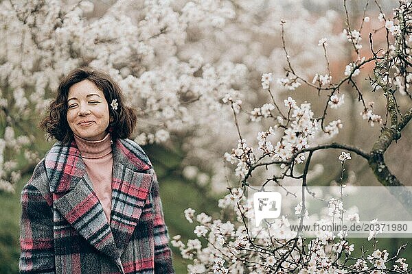 Young woman smiling in a blooming almond garden in Prague
