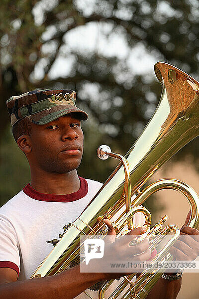 A young African American male military student stands firm holding his cornet.