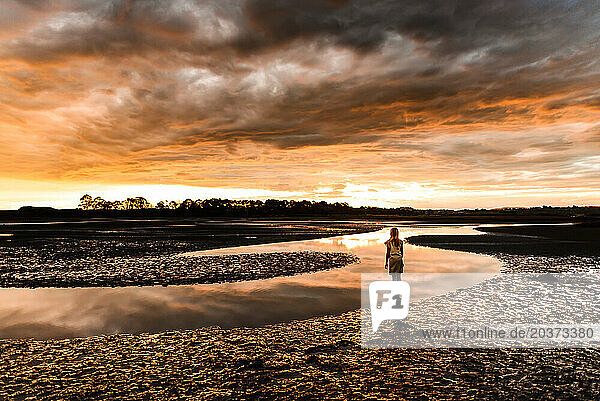 Girl watching beautiful sunset at an estuary in New Zealand