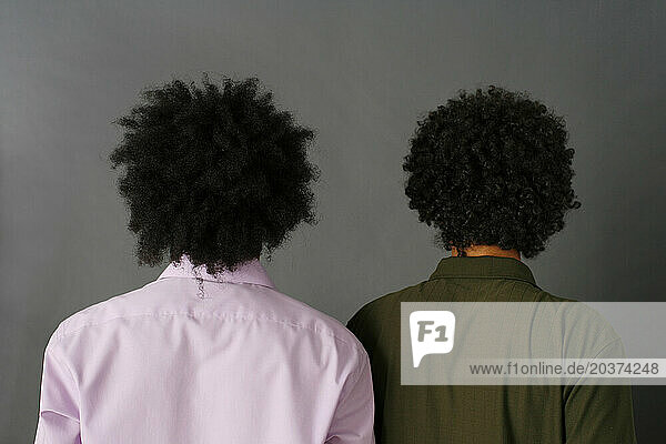 Two African American brothers with afros turn away from camera.