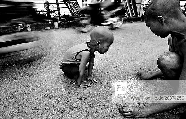 Mother picks up rice on street while son watches  in Hanoi  Vietnam.